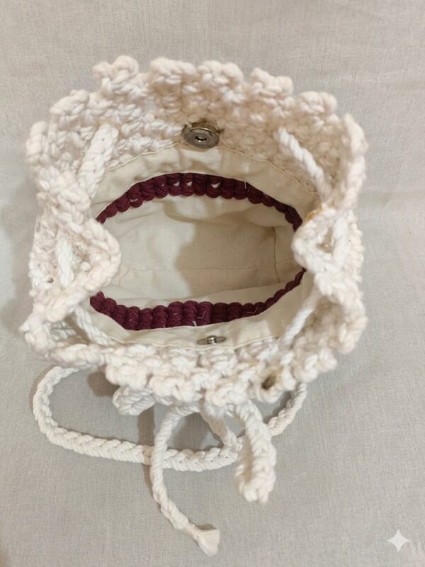Handmade macrame potli bag in white with drawstring closure styled with casual outfit on wooden table